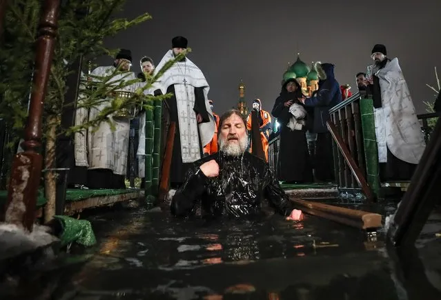 Russian Orthodox priest takes a dip in the ice cold water of a pond during the celebrations of the Orthodox Epiphany holiday, in Moscow, Russia, 18 January 2023. People believe that dipping into blessed waters during the holiday of Epiphany strengthens their spirit and body. (Photo by Yuri Kochetkov/EPA/EFE)
