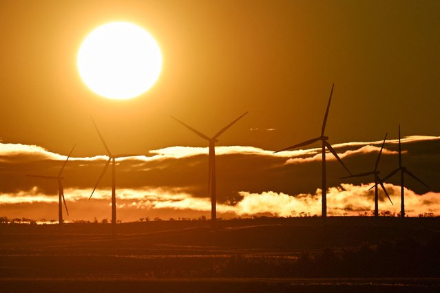 Wind turbines are silhouetted during sunrise in the Snowy Mountains region of New South Wales, Australia on July 28, 2025. (Photo by Saeed Khan/AFP Photo)