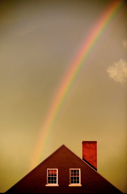 A rainbow settles behind the roof line of a building in Fredericksburg, Va., on Wednesday, August 20, 2014. (Photo by Peter Cihelka/AP Photo/The Free Lance-Star)