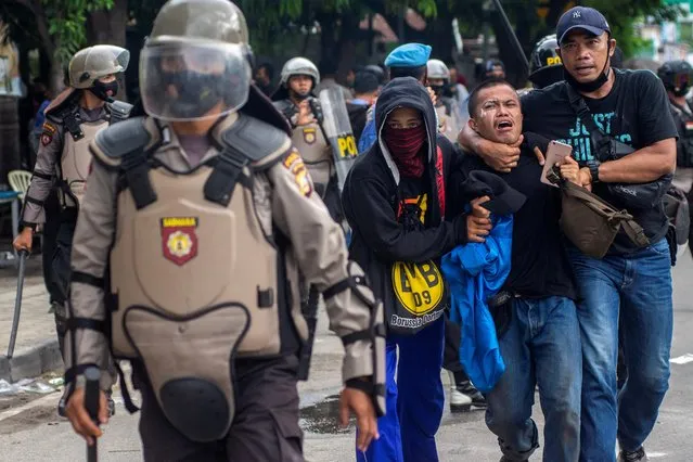 Plainclothes police officers detain a student-demonstrator during a protest against the government's labor reforms in Palu, Central Sulawesi province, Indonesia, October 8, 2020. (Photo by Basri Marzuki/Antara Foto via Reuters)