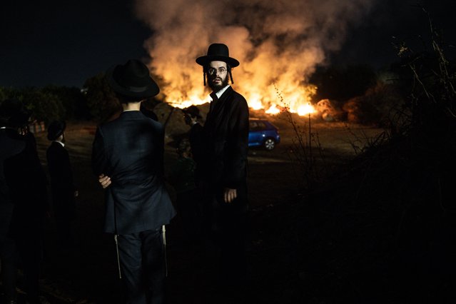 An Ultra-Orthodox Jewish man stands in front of a burning fire during a protest against Israeli army conscription in Kfar Yona on August 19, 2025. Israel's ultra-Orthodox Jewish community pledged to resist government moves to call up seminary students for military service on August 7, as demonstrators took to the streets to protest the arrest of two objectors. The Israeli army announced in early July that tens of thousands of conscription orders would be sent out to ultra-Orthodox Jews. (Photo by John Wessels/AFP Photo)