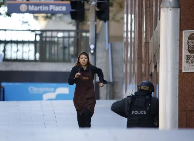 A hostage runs towards a police officer outside Lindt cafe, where other hostages are being held, in Martin Place in central Sydney December 15, 2014. (Photo by Jason Reed/Reuters)