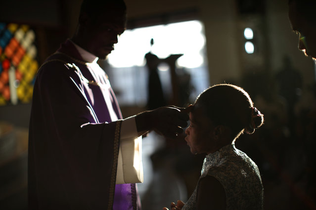 A priest marks with ash the forehead of a Catholic woman during a mass for Ash Wednesday at St Jean Bosco church in Petion-Ville, Port-au-Prince, February 14, 2018. (Photo by Andres Martinez Casares/Reuters)