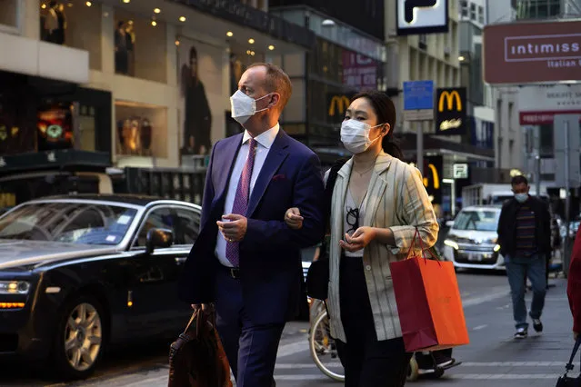 People wearing face masks to protect against the spred of the coronavirus, walk along a street in Hong Kong, Monday, November 30, 2020. (Photo by Kin Cheung/AP Photo)