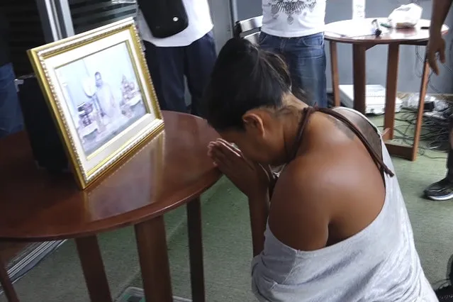 In this image made from video taken on Sunday, October 16, 2016, Umaporn Sarasat, 43, pays respects in front of a portrait of Thailand's King Bhumibol Adulyadej in Koh Samui, Thailand. She is accused of insulting the country's late king and was forced to kneel before his portrait outside a police station on the tourist island of Samui as several hundred people bayed for an apology. It is likely that Umaporn, a small-business owner, who is alleged to have posted disrespectful comments online, will face charges of insulting the monarchy. Thailand has draconian lese majeste laws that impose stiff prison sentences for actions or writings regarded as derogatory toward the monarch or his family. (Photo by AP Photo)