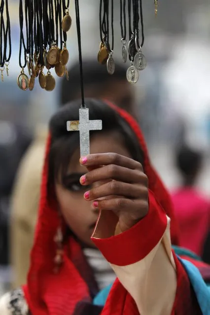A girl checks a cross pendent at a stall in the premises of the St John's Cathedral Church, on Christmas day in Peshawar December 25, 2014. (Photo by Fayaz Aziz/Reuters)