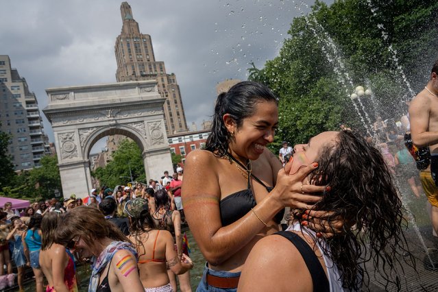 Two people embrace in the fountain at Washington Square Park after the New York City Pride March on June 30, 2024, in New York City. (Photo by Adam Gray/AFP Photo)