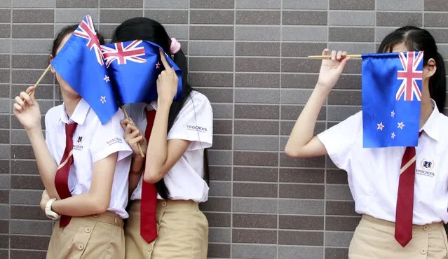Vietnamese students cover their faces with New Zealand's flags while they wait for arrival of Prime Minister John Key at Vin School in Hanoi, Vietnam November 16, 2015. (Photo by Reuters/Kham)