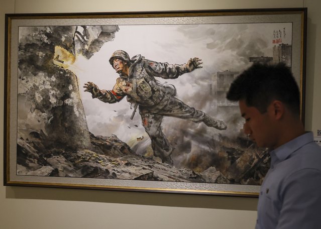 A visitor walks past the painting the painting 'Giving My Priceless Life' by Chwe Il Bon, San Gum Chehor and Kim Cheol Yung during the first North Korean arts exhibition, titled “The Country of a Great People” in Moscow, Russia, 08 October 2025. The first overseas exhibition of works by North Korean artists features 123 works, including Korean national paintings (Joseon hwa), prints, ceramics, mosaics, and embroidery. A key focus of the exhibition was the comradely relations between Russia and the DPRK during the liberation of the Kursk region. (Photo by Sergei Ilnitsky/EPA)