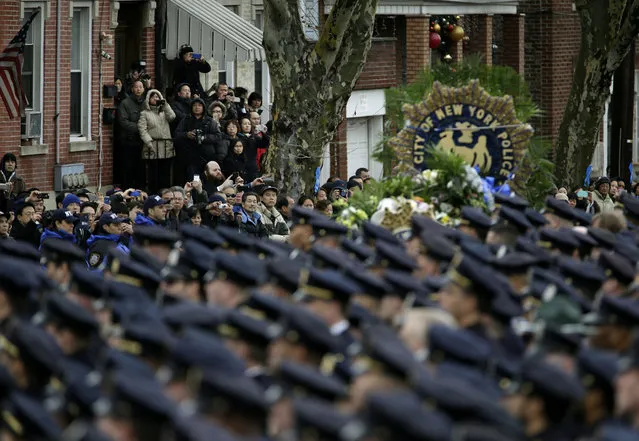 Spectators watch as the funeral procession for Officer Wenjian Liu passes in the Brooklyn borough of New York, Sunday, January 4, 2015. (Photo by Seth Wenig/AP Photo)