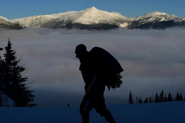 Rob Kenney hikes on Wildcat Mountain above undercast clouds across the valley from 5,793-foot Mt. Adams, background, Monday, January 30, 2023, in New Hampshire. Kenney and a friend are making an overnight hike as part of long-term quest to hike the state's 48 4,000-foot mountains. (Photo by Robert F. Bukaty/AP Photo)
