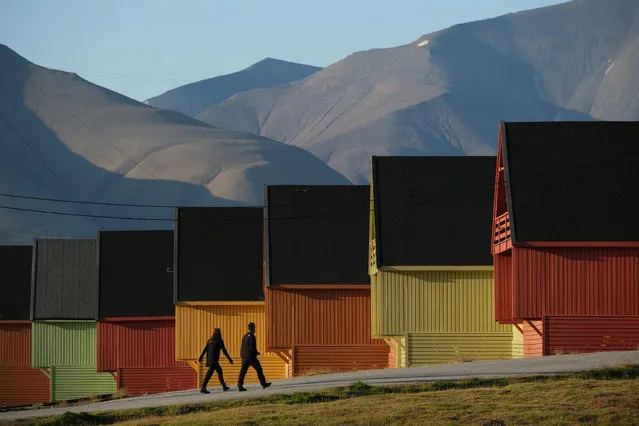 People walk past houses as mountains devoid of snow stand behind during a summer heat wave on Svalbard archipelago on July 30, 2020 in Longyearbyen, Norway. Svalbard archipelago, which lies approximately 1,200km north of the Arctic Circle, is currently experiencing a summer heat wave that set a new record in Longyearbyen on July 25 with a high of 21.7 degrees Celsius. Global warming is having a dramatic impact on Svalbard that, according to Norwegian meteorological data, includes a rise in average winter temperatures of 10 degrees Celsius over the past 30 years, creating disruptions to the entire local ecosystem. (Photo by Sean Gallup/Getty Images)