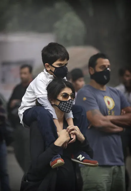A boy sits on the shoulder of his mother as they participate in a protest against air pollution in New Delhi, India, Sunday, November 6, 2016. Even for a city considered one of the worlds dirtiest, the Indian capital hit a new low this week. Air so dirty you can taste and smell it; a gray haze that makes a gentle stroll a serious health hazard. According to one advocacy group, government data shows that the smog that enveloped the city midweek was the worst in the last 17 years. (Photo by Manish Swarup/AP Photo)