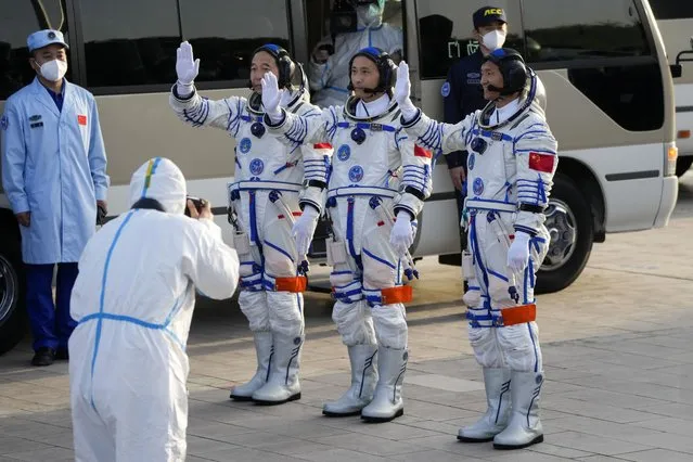 Chinese astronauts for the Shenzhou-16 mission, from left, Jing Haipeng, Zhu Yangzhu and Gui Haichao wave as they prepare to board for liftoff for their manned space mission at the Jiuquan Satellite Launch Center in northwestern China, Tuesday, May 30, 2023. (Photo by Mark Schiefelbein/AP Photo)