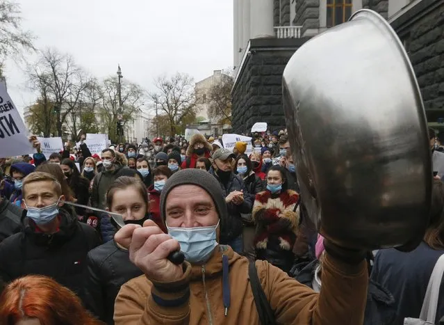 Workers of restaurant businesses bang on pans in a sign of protest against the newly introduced coronavirus weekend quarantine in front of the Cabinet in Kyiv, Ukraine, Wednesday, November 11, 2020. Ukraine's Cabinet has ruled to introduce a weekend quarantine, allowing to work only food stores, pharmacies, public transport and gas stations in an attempt to fight against raising COVID-19 cases in Ukraine. (Photo by Efrem Lukatsky/AP Photo)