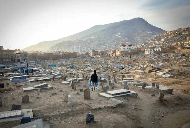 A boy searches for customers to sell water while walking across Kart-e Sakhi cemetery in Kabul, Afghanistan, 27 January 2021. According to Afghanistan's Human Rights Commission (AIHRC) report, more than 3,000 civilians have been killed and over 5,500 others were wounded in the conflicts in Afghanistan in 2020. (Photo by Hedayatullah Amid/EPA/EFE)