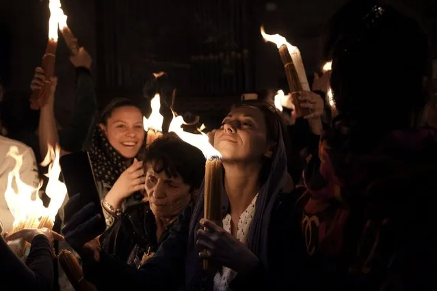 Christian pilgrims hold candles as they gather during the ceremony of the Holy Fire at Church of the Holy Sepulchre, where many Christians believe Jesus was crucified, buried and rose from the dead, in the Old City of Jerusalem dead, Saturday, April 23, 2022. (Photo by Maya Alleruzzo/AP Photo)