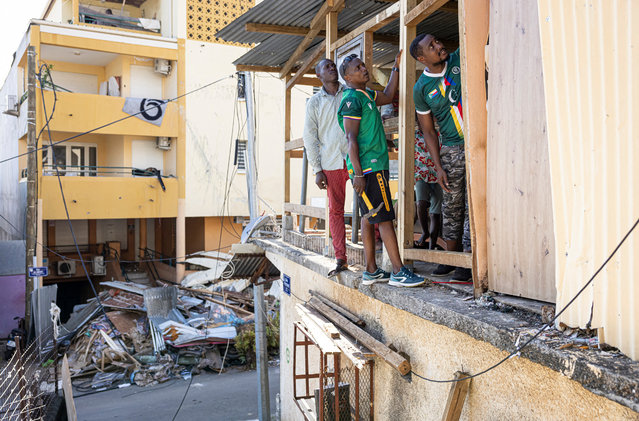 Residents fix the wall of a house in the city of Mamoudzou, on the French Indian Ocean territory of Mayotte, on December 21, 2024, after cyclone Chido hit the archipelago. Rescuers raced against time to reach survivors and supply urgent aid after the devastating cyclone Chido ripped through the French Indian Ocean territory of Mayotte, destroying homes across the islands. (Photo by Patrick Meinhardt/AFP Photo)