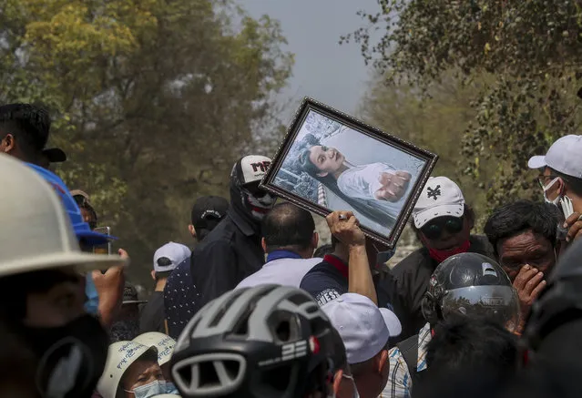 A man holds a picture of Kyal Sin during her burial in Mandalay, Myanmar, Thursday, March 4, 2021. Kyal Sin was shot in the head by Myanmar security forces during an anti-coup protest rally she was attending Wednesday. (Photo by AP Photo/Stringer)