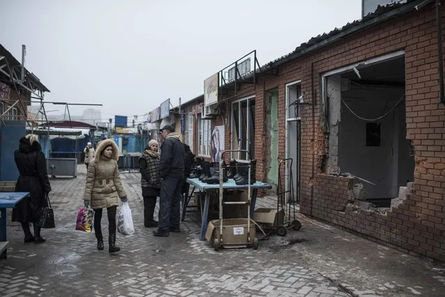 A woman walks past a building damaged by Saturday's shelling at the market in Mariupol, Ukraine, Wednesday, January 28, 2015. (Photo by Evgeniy Maloletka/AP Photo)