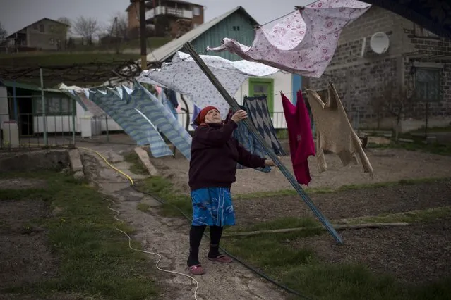 Local resident Lyudmila Shander takes her washing off the line in the village of Berdyanske near Shyrokyne, eastern Ukraine, Tuesday, April 14, 2015. Shyrokyne, a village on the Azov Sea that has been the epicenter of recent fighting, has changed hands repeatedly throughout the conflict.  (AP Photo/Evgeniy Maloletka)