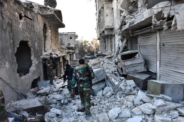 Syrian pro-government forces walk amidst heavy destruction in Aleppo's Bustan al-Basha neighbourhood on November 28, 2016, during their assault to retake the entire northern city from rebel fighters. In a major breakthrough in the push to retake the whole city, regime forces captured six rebel-held districts of eastern Aleppo over the weekend, including Masaken Hanano, the biggest of those in eastern Aleppo. (Photo by George Ourfalian/AFP Photo)