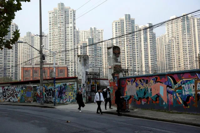 People walk in front of a wall painted with graffiti along a street in Shanghai, China December 1, 2016. (Photo by Aly Song/Reuters)