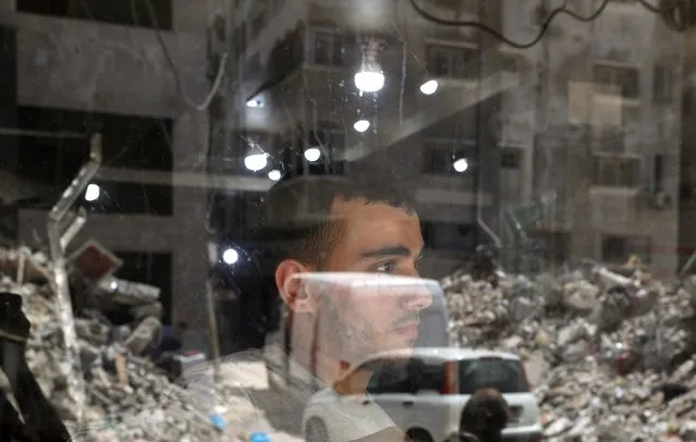 A Palestinian man looks out as the remains of a building, which was destroyed in Israeli air strikes, are reflected in a window, amid Israeli-Palestinian fighting, in Gaza, May 20, 2021. (Photo by Mohammed Salem/Reuters)