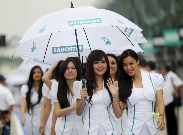 Malaysia Formula One grid girls pose for a picture under a Petronas umbrella prior to the third practice of the Malaysian F1 Grand Prix at the Sepang circuit outside Kuala Lumpur in this April 9, 2011 file photo. When Malaysian oil giant Petronas announced sharp spending cuts and described a dismal outlook this week, it was confirmation for millions that they will struggle to make ends meet this year amid high costs, a plunging currency and fewer jobs. (Photo by Bazuki Muhammad/Reuters)