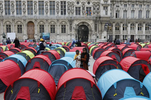 A woman migrant holds her baby in a makeshift camp set up outside the Paris town hall, Friday, June 25, 2021. More than 300 migrants set up some 200 tents outside the town hall to draw attention to their living conditions and to demand accommodation. (Photo by Lewis Joly/AP Photo)