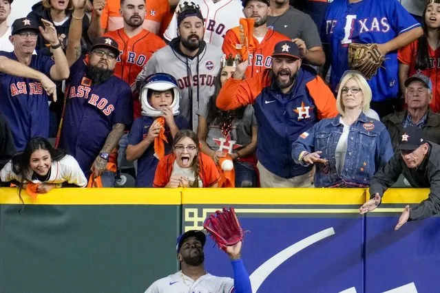 Fans try to distract Texas Rangers' Adolis Garcia as he catches a ball hit by Houston Astros' Jeremy Pena during the ninth inning of Game 2 of the baseball AL Championship Series Monday, October 16, 2023, in Houston. (Photo by Godofredo A. Vasquez/AP Photo)