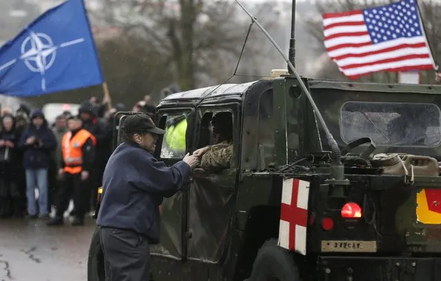 A supporter shakes hands with a US army soldier as their convoy arrives in Prague, Czech Republic, Monday, March 30, 2015. (Photo by Petr David Josek/AP Photo)