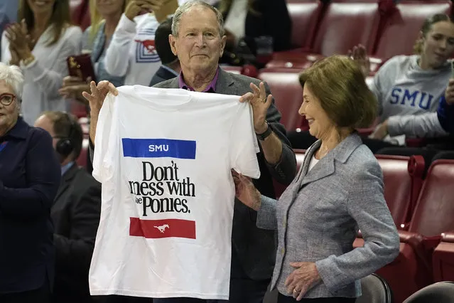 Former United States President George W. Bush, left, holds up a shirt with First Lady Laura Bush during an NCAA college basketball game between SMU and Texas A&M in Dallas, Tuesday, November 14, 2023. (Photo by L.M. Otero/AP Photo)