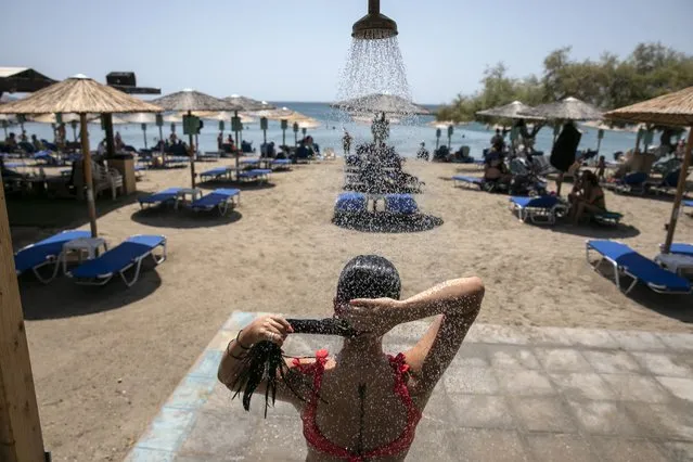A woman takes a shower at a beach of Lagonissi village, a few miles southwest of Athens, on Thursday, July 29, 2021. One of the most severe heat waves recorded since 1980s scorched southeast Europe on Thursday, sending residents flocking to the coast, public fountains and air-conditioned locations to find some relief, with temperatures rose above 40°C (104°F) in parts of Greece and across much of the region. (Photo by Yorgos Karahalis/AP Photo)