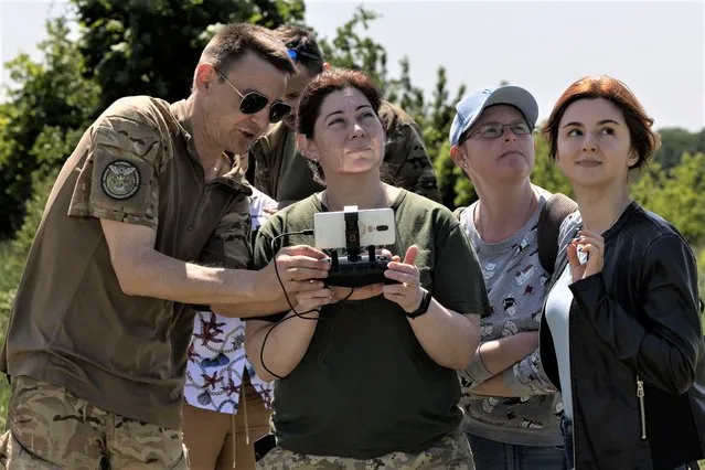 Dynamo, a Ukranian military drone instructor helps students from left, Ksenia Timofieva, Sasha Prokhorova and Oleksandra Yefymenko during a beginners drone class on May 20, 2023 in Kyiv region, Ukraine. The Female Pilots of Ukraine is the country's first school dedicated to teaching women this important new skill, both civilians as well as military. Drones are used for both reconnaissance and fighting. (Photo by Paula Bronstein /Getty Images)