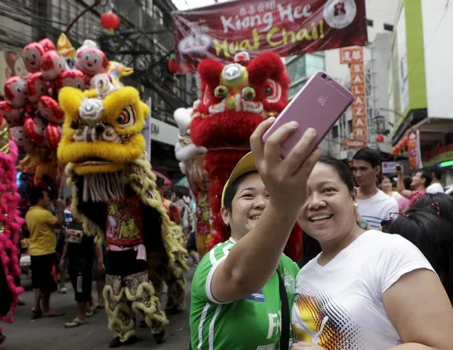 Residents take a selfie near lion dancers on the eve of the Chinese Lunar New Year in Manila's Chinatown, Philippines February 7, 2016. (Photo by Janis Alano/Reuters)