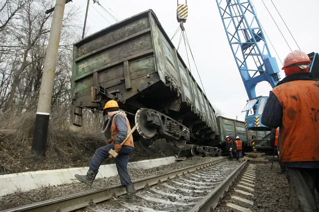 Workers remove a carriage of a train derailed after a blast on a rail track at a railway station in the rebel-controlled town of Yasynuvata, near Donetsk, Ukraine, February 17, 2016. According to the Minister of Transport of the self-proclaimed Donetsk People Republic, it was a blast of a device, which he did not specify. (Photo by Alexander Ermochenko/Reuters)