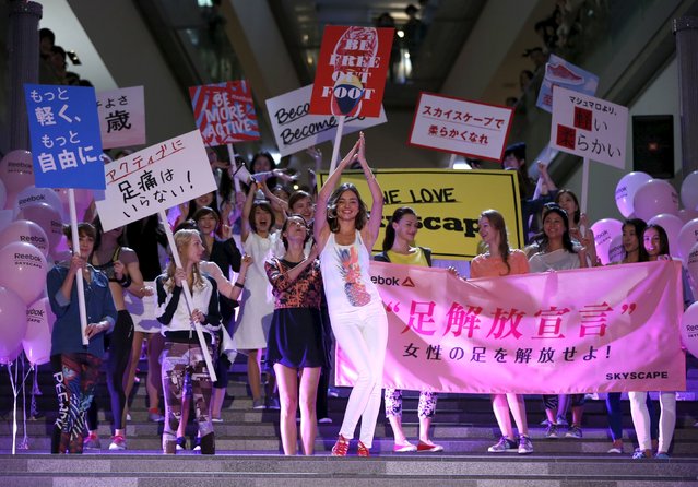 Australian model Miranda Kerr (C) leads women holding placards and a banner (R), which reads “Women be freed from bad-fitting shoes”, during a promotional event for the Reebok Skyscape shoes series at the Omotesando Hills in Tokyo April 15, 2015. (Photo by Issei Kato/Reuters)