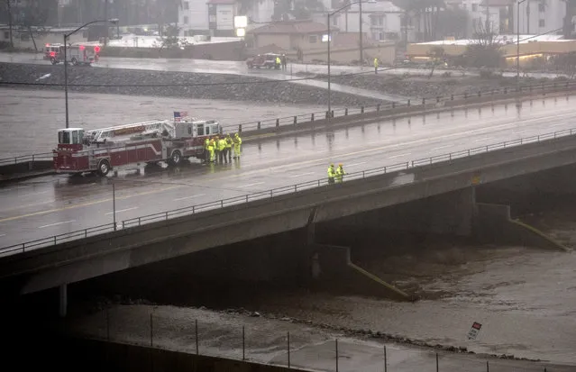 Fire units attempt to locate a possible person in Santa Ana River in Costa Mesa, Calif., during a storm Sunday, January 22, 2017. The heavy downpour on Sunday drenched Orange County in one of the heaviest storms of the year. Fast-moving floodwaters swept through California mountain communities and residents fled homes below hillsides scarred by wildfires as the third in the latest series of storms brought a deluge Sunday and warnings about damaging mudslides. (Photo by Kyusung Gong/The Orange County Register via AP Photo)