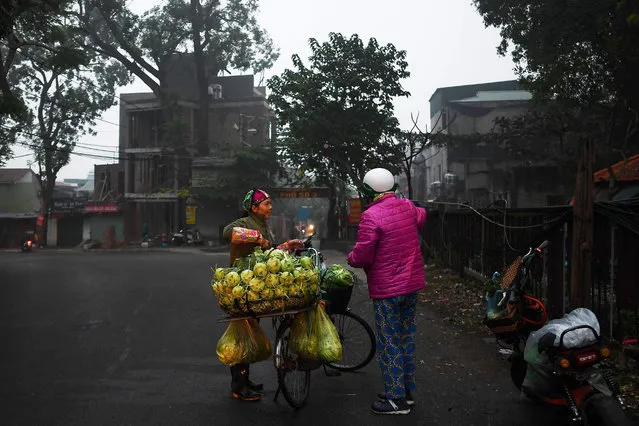 A Vietnamese vegetable vendor attends a customer at a street in the early morning in Hanoi on January 7, 2019. (Photo by Manan Vatsyayana/AFP Photo)