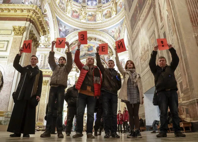 Protesters against the transfer of St. Isaac's Cathedral to the Russian Orthodox Church hold letters reading “The museum!” standing inside the St. Isaac's Cathedral in St.Petersburg, Russia, Saturday, January 28, 2017. Over 2,000 people rallied in St. Petersburg on Saturday to protest plans by the city authorities to give a landmark cathedral to the Russian Orthodox Church amid an increasingly passionate debate over the relationship between the church and state. (Photo by Dmitri Lovetsky/AP Photo)
