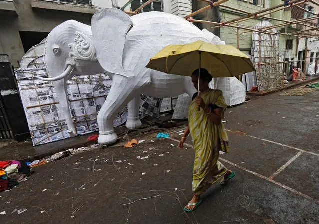 A woman uses an umbrella to take cover from rain as she walks past a model of elephant which will be used to decorate a pandal, or a temporary platform, during the Hindu festival of Saraswati Puja, the goddess of education, in Kolkata, India, January 27, 2017. (Photo by Rupak De Chowdhuri/Reuters)