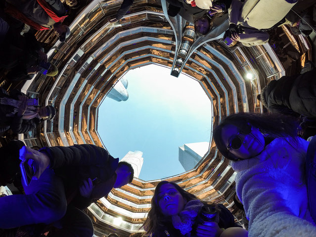 Visitors try to get the best picture with their phones and cameras at the center of “The Vessel” a public art structure on the West Side of Midtown Manhattan in New York, United States on March 20, 2019. The elaborate honeycomb-like structure Vessel designed by the British designer Thomas Heatherwick, its consisting of 154 flights of stairs at Hudson Yards 2,500 steps, and 80 landings that visitors would be able to climb. Phase one of the Hudson Yards real-estate development project, which cost about 25 billion US dollars, opened on Friday. (Photo by Atilgan Ozdil/Anadolu Agency/Getty Images)