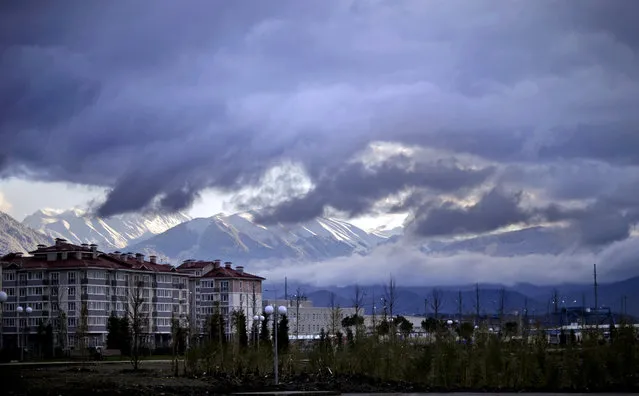 The Caucasus Mountains, site of the 2014 Winter Olympic outdoor snow sport and sliding track events, rise above a recently built housing complex, at left, near the Olympic Park by the Black Sea in the Coastal Cluster, Saturday, February 1, 2014, in Sochi, Russia. (Photo by David Goldman/AP Photo)