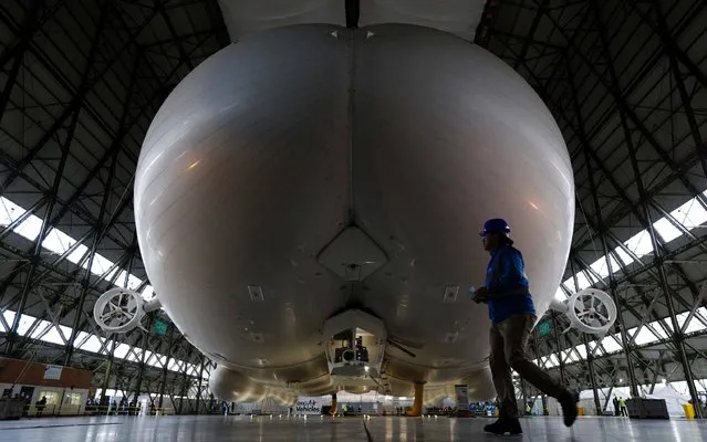 The Airlander 10 airship is pictured airborne in its hangar during its media launch at Cardington Airfield in Shortstown near Bedford on March 21, 2016. The Airlander, which was originally developed for the US military, is 300 feet (91 metres) long, according its British maker Hybrid Air Vehicles. The Airlander is essentially three streamlined airship-type bodies merged into one with wings and rotary engines. (Photo by Adrian Dennis/AFP Photo)