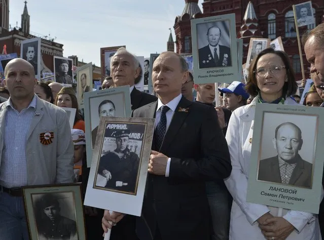 Russian President Vladimir Putin (C) holds a portrait of his father, war veteran Vladimir Spiridonovich Putin as he takes part in the Immortal Regiment march on the Red Square during the Victory Day celebrations in Moscow, Russia, May 9, 2015. (Photo by Reuters/Host Photo Agency/RIA Novosti)
