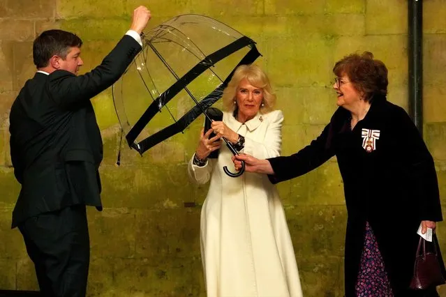 Britain's Queen Camilla (C) hands her umbrella to an aide as she arrives for a Musical Evening at Salisbury Cathedral, in Salisbury, England, on February 8, 2024, to celebrate the work of local charities. (Photo by Kirsty Wigglesworth/Pool via AFP Photo)