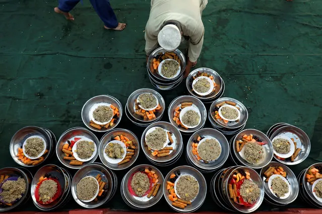A volunteer arranges food plates for the people to break fast during the fasting month of Ramadan at a mosque in Karachi, Pakistan, May 7, 2019. (Photo by Akhtar Soomro/Reuters)