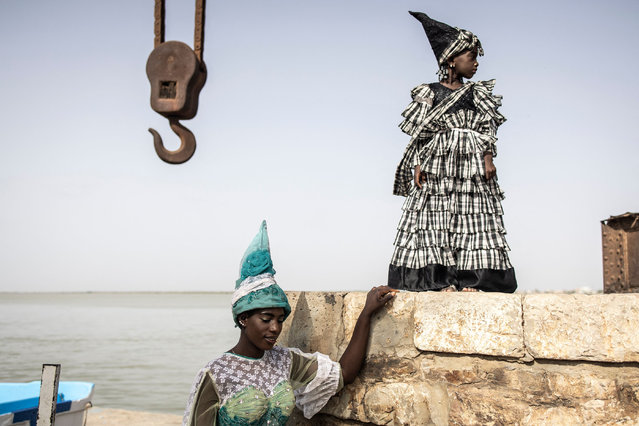 Models working with fashion designer, Ndeye Diop Guisse, poses for a portrait in front of a disused port crane, whilst wearing traditional Signares outfits in Saint Louis on August 10, 2021. The Signares were traditionally mixed European-African women in the eighteenth and nineteenth centuries from Goree Island and Saint Louis in Senegal, they held positions of power, status and wealth with-in the Atlantic slave-trade business and where know for their lavish outfits and Jewellery. (Photo by John Wessels/AFP Photo)