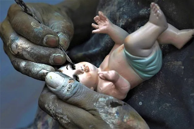 A man repairs a Baby Jesus figure in Mexico City, Wednesday, January 25, 2023. As Mexicans prepare to celebrate “Dia de la Candelaria” or Candlemas. people bring in their Baby Jesus figures for major repairs. (Photo by Marco Ugarte/AP Photo)